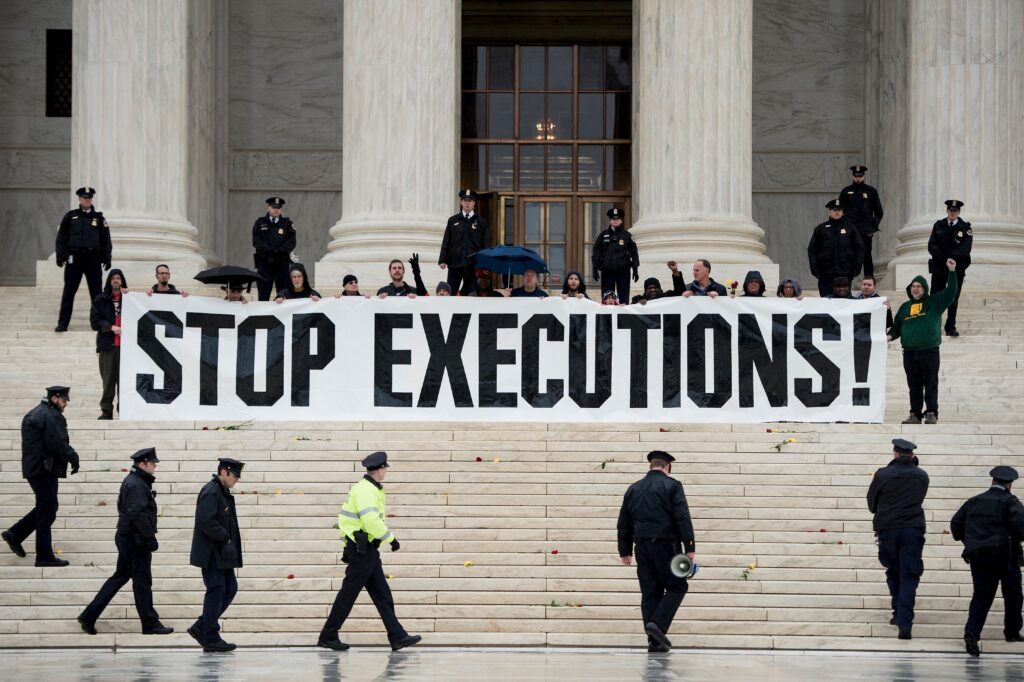 The image shows protestors being prevented from calling for a Stop to Executions by police in the US.